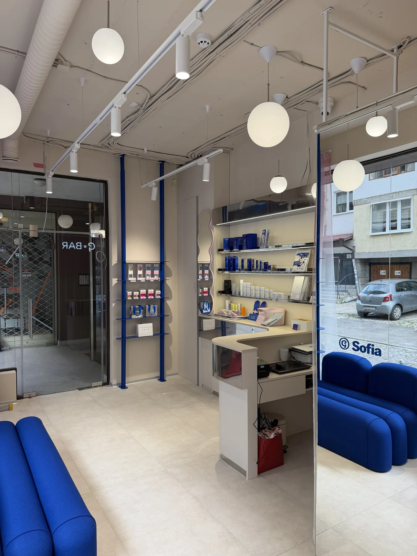 G-Bar Sofia glass storefront with salon entrance, display shelves and blue lounge seating
