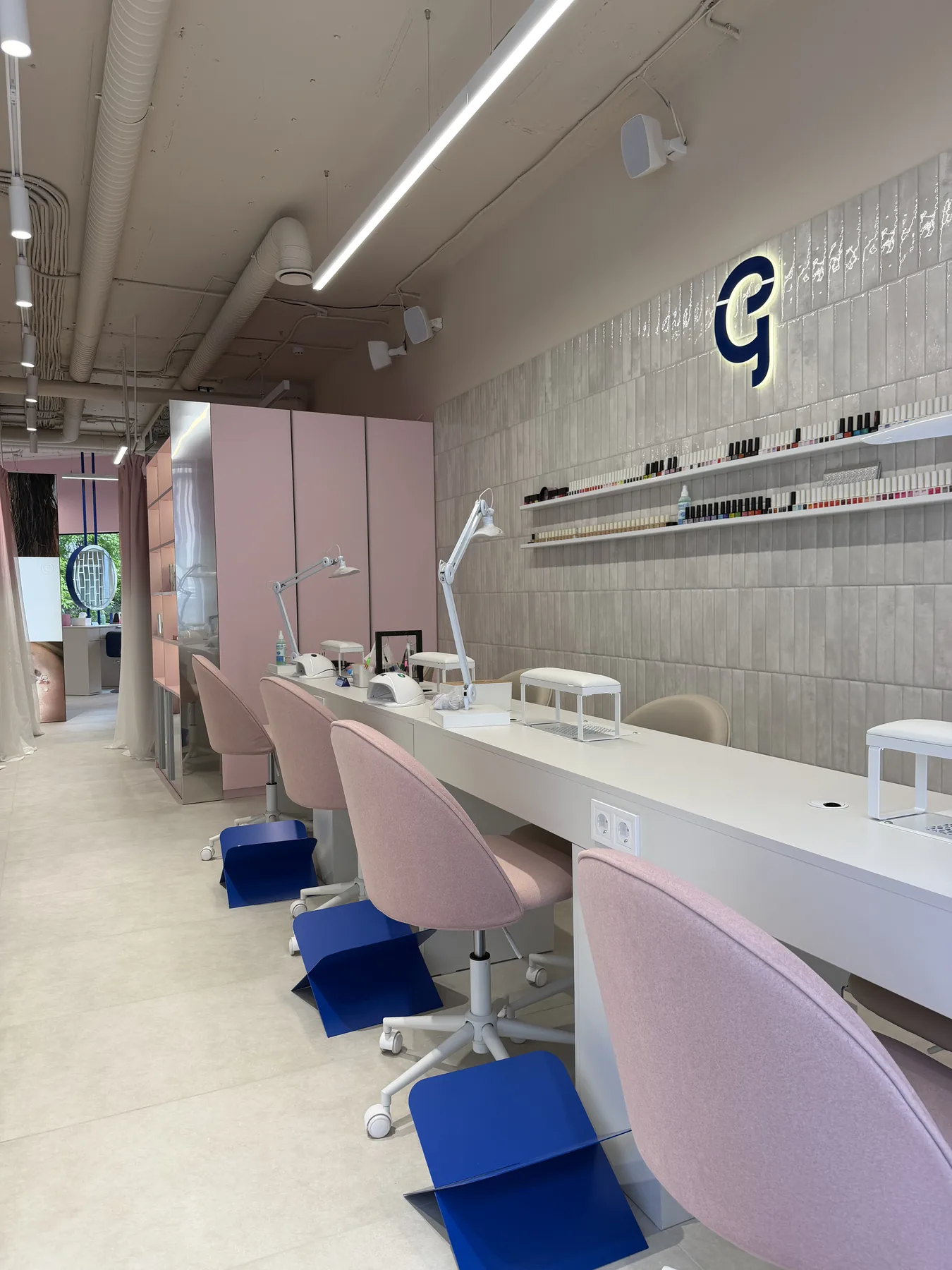 Finished manicure stations with counters, task lighting and pink salon seating