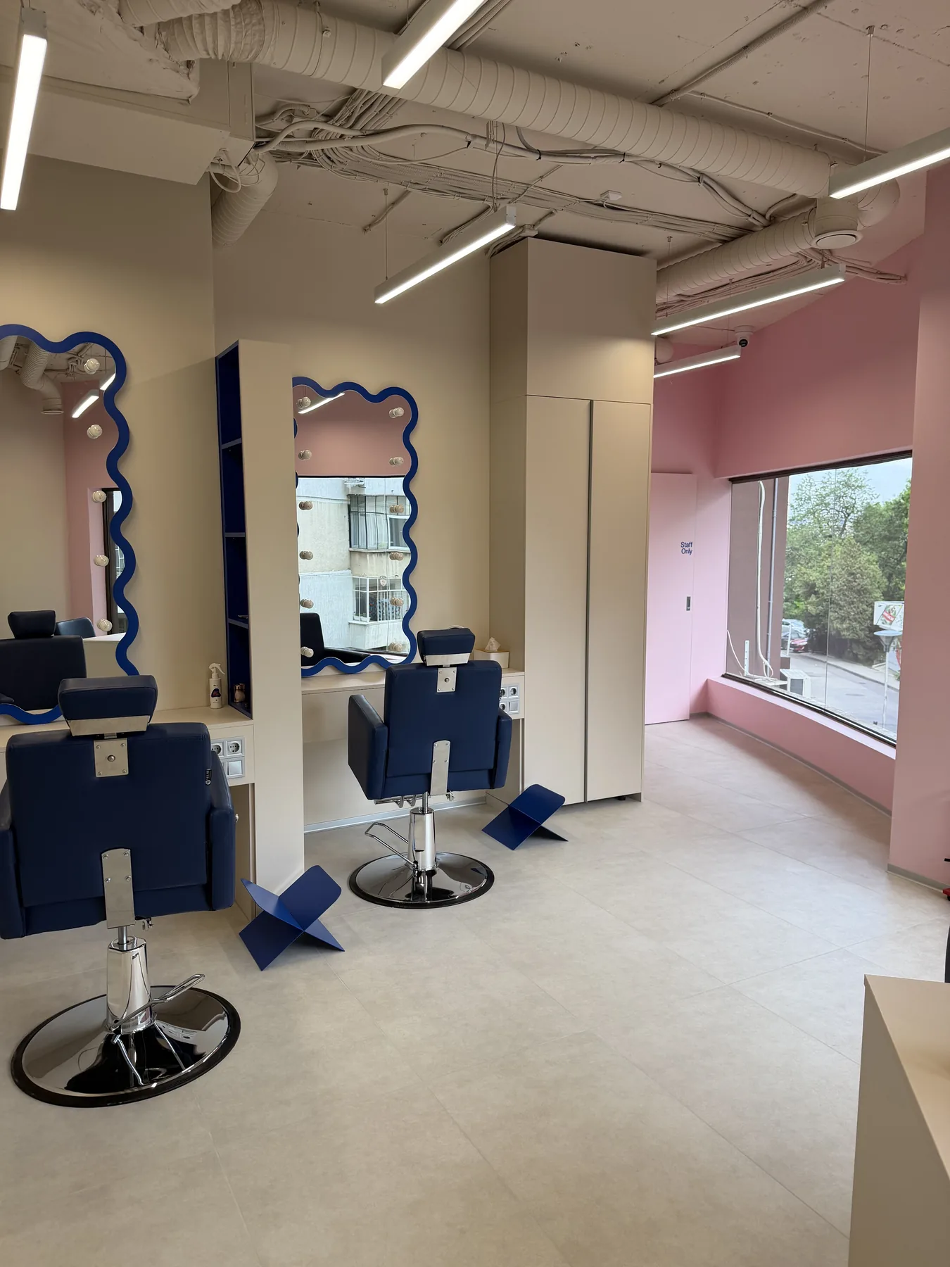Hair styling area with mirrors and blue salon chairs in the completed G-Bar interior