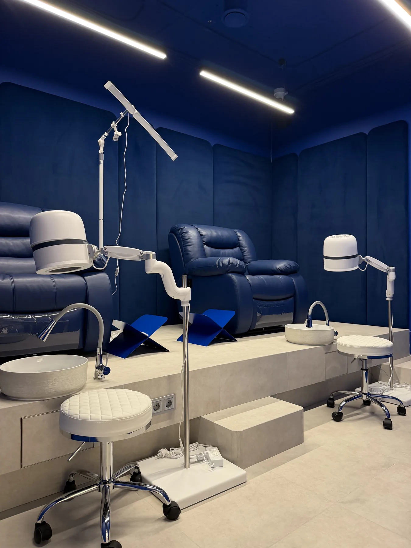 Blue pedicure room with raised platforms, recliners and task lighting