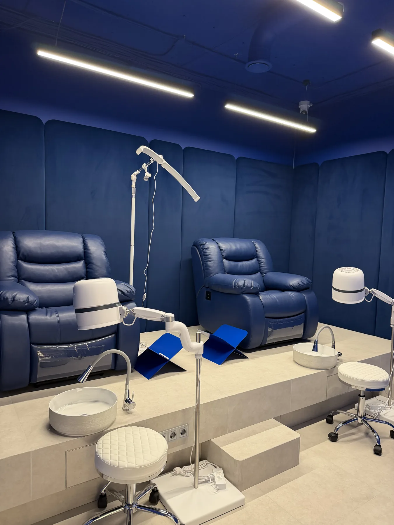 Pedicure stations with blue walls, seating and task lighting