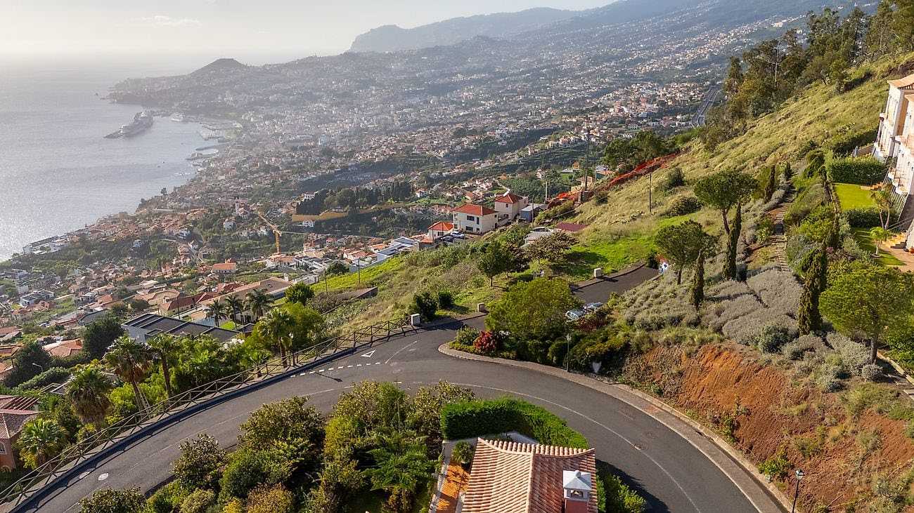Hillside road and landscaped plots with wide view over Funchal city and the ocean